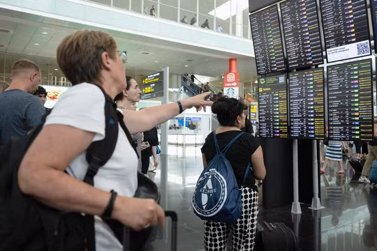 Hành khách nhìn vào màn hình hiển thị các chuyến bay bị trì hoãn tại sân bay Barcelona vào ngày 19/7, ở Barcelona, ​​​​Tây Ban Nha (Ảnh: Getty)