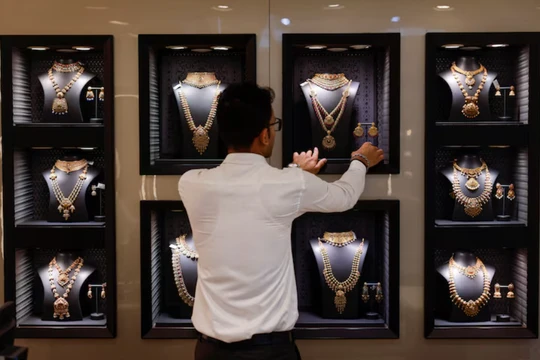 Một nhân viên đang sắp xếp vòng cổ vàng tại một cửa hàng trang sức ở Mumbai, Ấn Độ, ngày 20/3. Ảnh: Reuters.