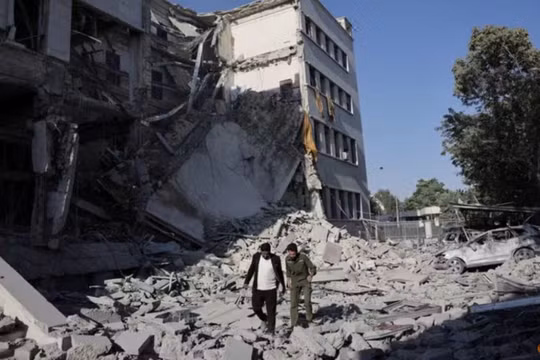 Người dân đi bộ giữa đống đổ nát sau cuộc không kích mạnh mẽ của Israel làm rung chuyển Damascus vào ngày 16/7. Ảnh: Reuters.