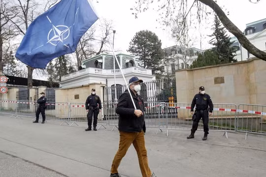 Một người đàn ông mang cờ NATO trước cửa Đại sứ quán Nga ở Praha, CH Séc (Ảnh: RT)