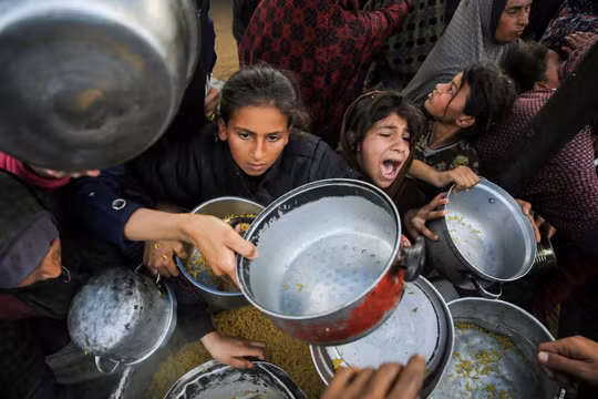 Người Palestine tụ tập để nhận thức ăn do một bếp từ thiện nấu ở Khan Younis, phía nam Dải Gaza, ngày 17/1. Ảnh: Reuters.