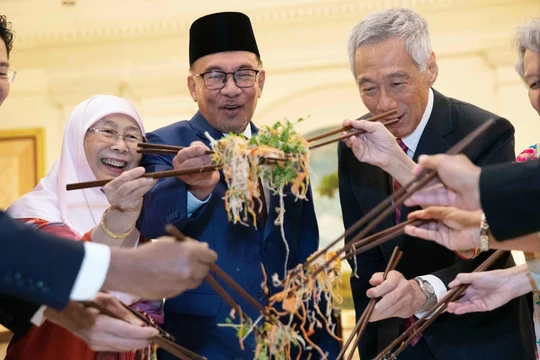 Các chính trị gia, bao gồm Thủ tướng đương nhiệm Singapore Lawrence Wong (trái) và Thủ tướng Malaysia Anwar Ibrahim (thứ ba từ trái sang), trộn một đĩa Yusheng trong lễ đón Tết Nguyên đán năm 2023. Ảnh: AFP.