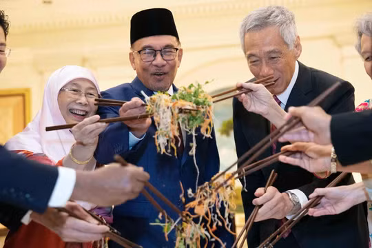 Các chính trị gia, bao gồm Thủ tướng đương nhiệm Singapore Lawrence Wong (trái) và Thủ tướng Malaysia Anwar Ibrahim (thứ ba từ trái sang), trộn một đĩa Yusheng trong lễ đón Tết Nguyên đán năm 2023. Ảnh: AFP.