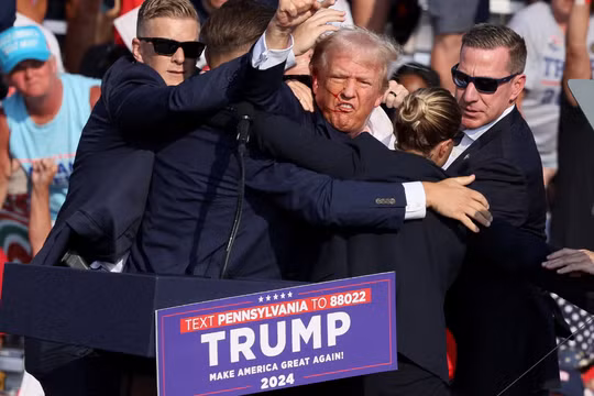 Ông Donald Trump ra hiệu với khuôn mặt đầy máu sau khi bị bắn vào tai phải trong một cuộc vận động tranh cử ở Butler, Pennsylvania, Mỹ ngày 13/7/2024. Ảnh: Reuters.