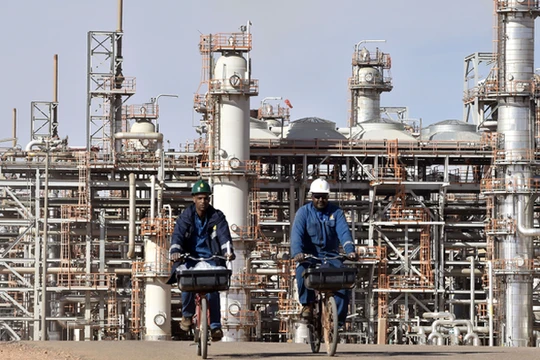 Hai công nhân bên ngoài một cơ sở sản xuất khí đốt ở Algeria (Ảnh: AFP).