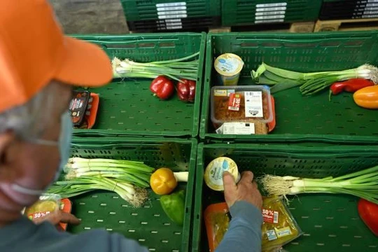 Một tình nguyện viên đang sắp xếp thực phẩm vào các giỏ hàng tại Bochum, Đức (Ảnh: AFP)