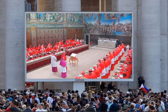 Mọi người xem màn hình tại Quảng trường Thánh Peter chiếu hình ảnh các hồng y bên trong Nhà nguyện Sistine, vào ngày đầu tiên của mật nghị bầu Giáo hoàng tiếp theo, tại Vatican, ngày 7/5. Ảnh: Reuters.