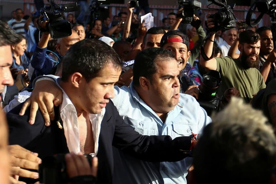Ông Juan Guaido được hộ tống ra xe để thoát khỏi đám đông người biểu tình ở sân bay (Ảnh: Sputnik)