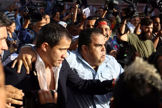 Ông Juan Guaido được hộ tống ra xe để thoát khỏi đám đông người biểu tình ở sân bay (Ảnh: Sputnik)