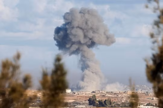 Khói bốc lên từ một vụ nổ ở Gaza, khi mọi người tham dự lễ tưởng niệm hai năm ngày xảy ra vụ tấn công chết người vào Israel ngày 7/10/2023, tại Kibbutz Kfar Aza. Ảnh: Reuters.