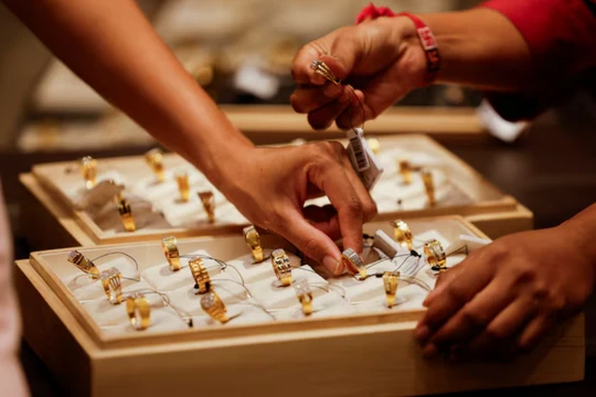 Một nhân viên bán hàng giới thiệu nhẫn vàng cho khách mua tại một phòng trưng bày trang sức ở Ahmedabad, Ấn Độ, ngày 8/10. Ảnh: Reuters.