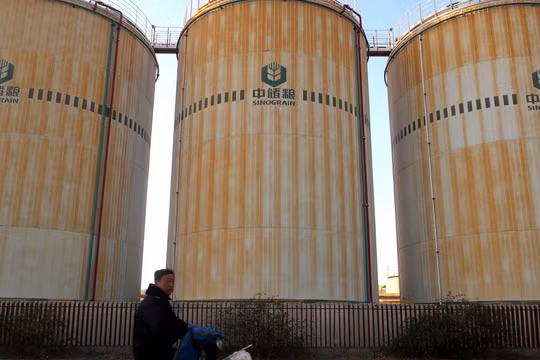 Một người đàn ông đạp xe ngang qua cơ sở lưu trữ của công ty Sinograin gần cảng Thiên Tân năm 2019 (Ảnh: Reuters)