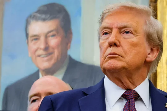 Tổng thống Donald Trump, trước bức tranh của cố Tổng thống Ronald Reagan, tại Phòng Bầu dục ở Nhà Trắng ở Washington, D.C. Ảnh: Reuters.