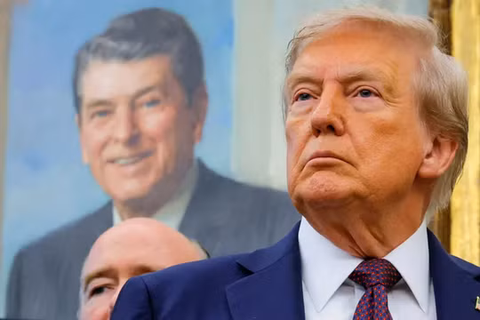Tổng thống Donald Trump, trước bức tranh của cố Tổng thống Ronald Reagan, tại Phòng Bầu dục ở Nhà Trắng ở Washington, D.C. Ảnh: Reuters.