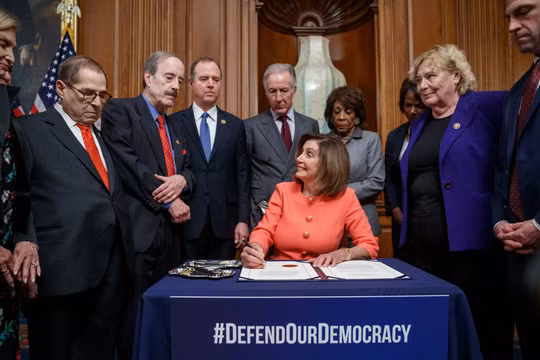 Chủ tịch Hạ viện Nancy Pelosi ký 2 điều khoản luận tội Trump để chuyển cho Thượng viện (Ảnh: Guardian)