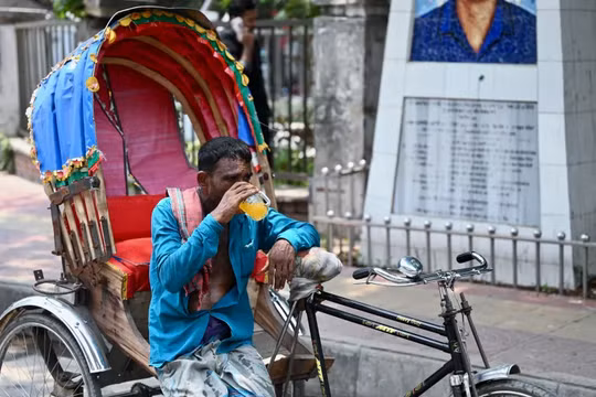 Người đàn ông với chiếc xe kéo tạm nghỉ để uống nước cam giải khát giữa đợt nắng nóng khủng khiếp ở Dhaka, Bangladesh (Ảnh: AFP)