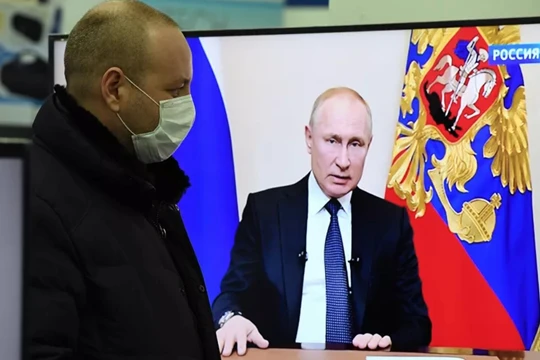 Một người dân theo dõi ông Putin phát biểu trên truyền hình (Ảnh: Sputnik)