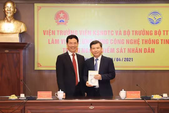 Bộ trưởng Nguyễn Mạnh Hùng tặng cuốn "Cẩm nang chuyển đổi số" cho Viện trưởng VKSNDTS Lê Minh Trí. Ảnh: VKSNDTC
