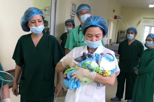 Nhóm bác sĩ đưa em bé mới sinh tới Bệnh viện Phụ sản Trung ương để chăm sóc