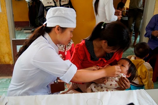 Cán bộ y tế cho trẻ uống vitamin A