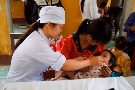 Cán bộ y tế cho trẻ uống vitamin A