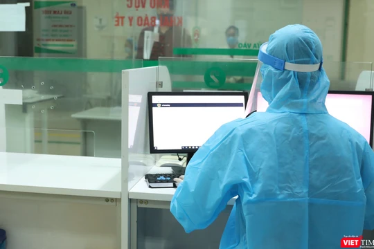 Nhân viên y tế ngồi tại phòng có vách ngăn vẫn hướng dẫn được bệnh nhân khai báo. Ảnh: Hồng Trần.