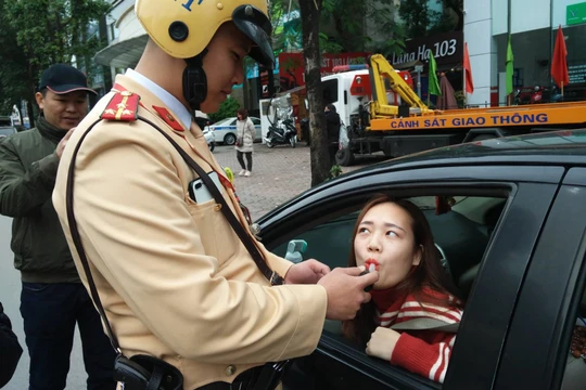 Người phụ nữ lái ô tô vui vẻ thổi kiểm tra nồng độ cồn. Ảnh: Hiệp Bình.