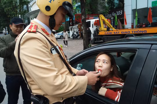 Người phụ nữ lái ô tô vui vẻ thổi kiểm tra nồng độ cồn. Ảnh: Hiệp Bình.
