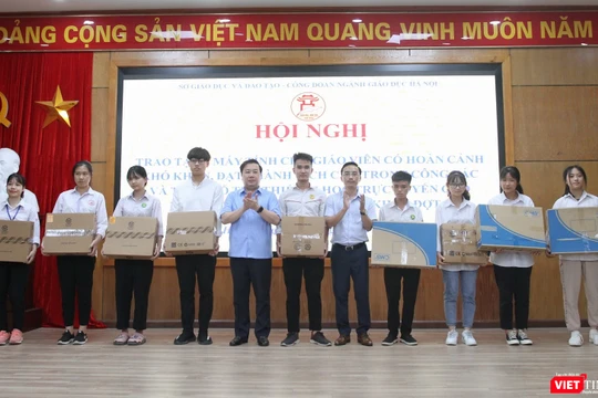 Giám đốc Sở GDĐT Hà Nội Chử Xuân Dũng và Hiệu trưởng trường THCS Thái Thịnh Nguyễn Cao Cường (đại diện nhà tài trợ) trao máy tính cho học sinh có hoàn cảnh khó khăn. Ảnh: Minh Ngọc.
