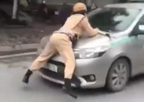 Hình ảnh Trung úy CSGT bị hất tung lên nắp capô taxi vào chiều nay. Ảnh chụp màn hình video: Anh Lê