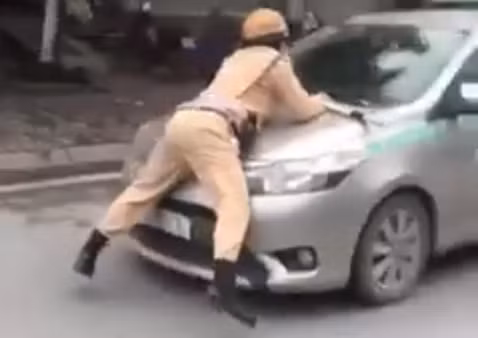 Hình ảnh Trung úy CSGT bị hất tung lên nắp capô taxi vào chiều nay. Ảnh chụp màn hình video: Anh Lê
