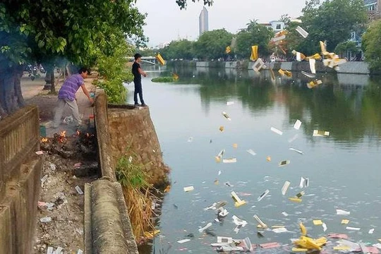 Hai người đàn ông thản nhiên đốt và ném vàng mã xuống sông