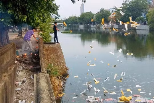 Hai người đàn ông thản nhiên đốt và ném vàng mã xuống sông