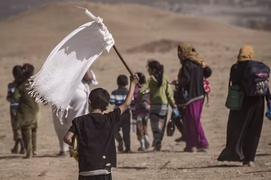 Một em nhỏ cầm cờ trắng trong dòng người chạy thoát khỏi Mosul