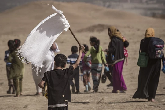 Một em nhỏ cầm cờ trắng trong dòng người chạy thoát khỏi Mosul