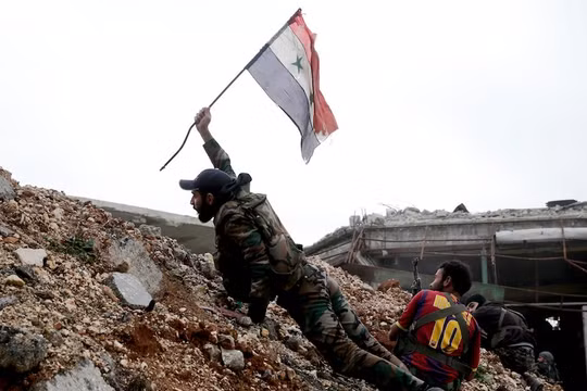 Một binh sĩ trong quân đội của chính phủ Syria cắm lá cờ quốc gia trong một trận chiến với các nhóm phiến quân tại tiền tuyến Ramouseh nằm tại phía đông thành phố Aleppo vào ngày 5.12.2016.