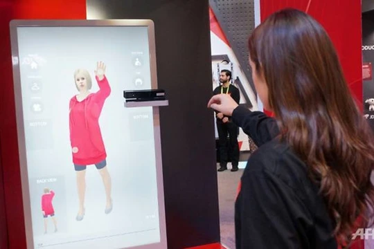 Nhân viên JD.com giới thiệu hệ thống AR cho phép khách hàng thử đồ ảo tại shop. Ảnh: AFP.