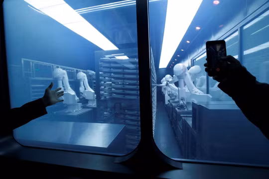 Một khách hàng chụp ảnh một cánh tay robot thu thập các món ăn đóng gói sẵn từ kho lạnh tại nhà hàng lẩu trí tuệ nhân tạo mới của Haidilao ở Bắc Kinh, Trung Quốc. Ảnh: Reuters