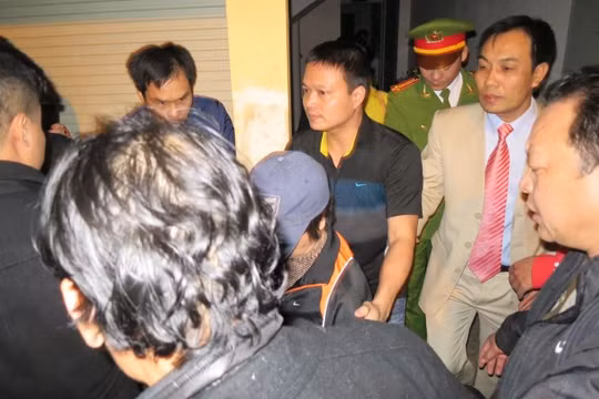 Bà Châu Thị Thu Nga (giữa, chụp mũ) bị bắt giữ và dẫn giải về trại giam vào tối khuya 7-1