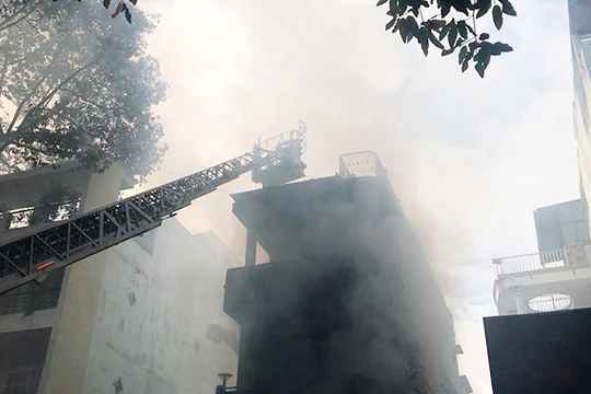 Lực lượng PCCC phải dung xe thang chuyên dung tiếp cận nóc ngôi nhà bị cháy ở Q.5 (TP.HCM) sáng nay.