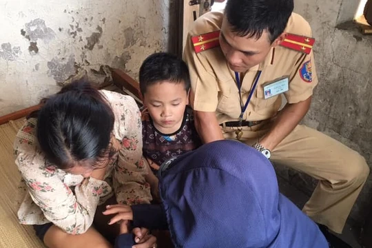 Người phụ nữ và đứa con trai nhỏ được cán bộ công an và người dân động viên tinh thần.