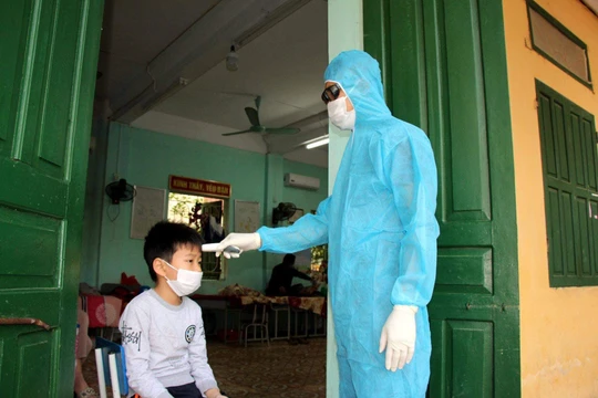 Nhân viên y tế kiểm tra nhiệt độ cho trẻ (Ảnh - HY) 