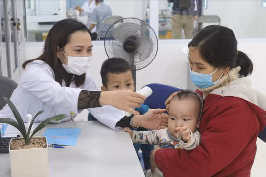 Nhân viên y tế kiểm tra nhiệt độ cho trẻ (Ảnh - Minh Thuý) 