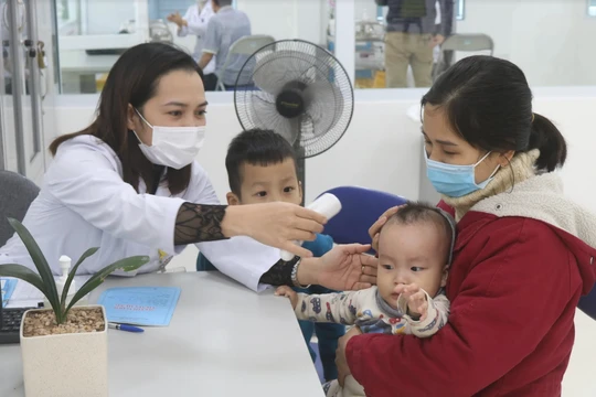 Nhân viên y tế kiểm tra nhiệt độ cho trẻ (Ảnh - Minh Thuý) 