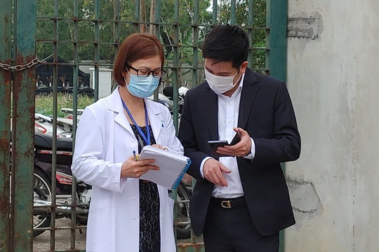 Nhân viên y tế làm việc bên ngoài cổng Trường Tiểu học Xuân Phương vào chiều qua (1/2) (Ảnh - Khánh Linh) 