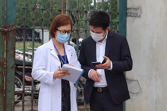 Nhân viên y tế làm việc bên ngoài cổng Trường Tiểu học Xuân Phương vào chiều qua (1/2) (Ảnh - Khánh Linh) 