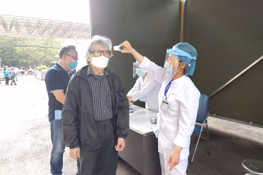 Nhân viên y tế kiểm tra thân nhiệt cho người dân (Ảnh: Minh Thuý) 