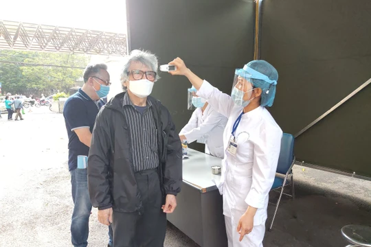 Nhân viên y tế đo thân nhiệt cho người dân tại Bệnh viện Hữu Nghị. Ảnh: Minh Thúy