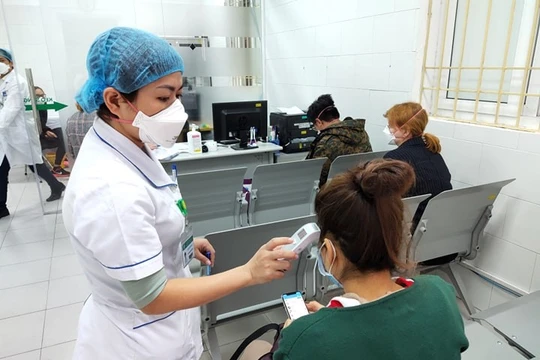 Bác sĩ đo nhiệt độ cơ thể cho người bệnh. Ảnh: Minh Thúy