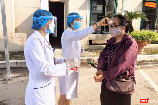 Nhân viên y tế kiểm tra nhiệt độ của người dân (Ảnh - Minh Thuý) 